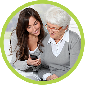 Young woman helping an older woman make a call on a smartphone.